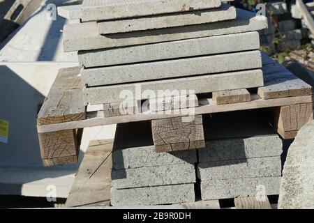 Concrete plates or cobble stones of large dimension piled on wooden pallets in the storage of building or construction material, close up view Stock Photo