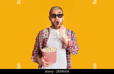 Surprised man in 3D glasses eating popcorn Stock Photo