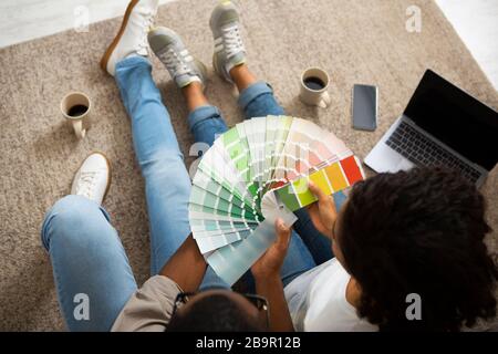African american girl and man with color swatch in hands sitting on floor Stock Photo