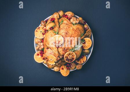Roasted chicken with oranges, rosemary and cranberries on plate over concrete background. Traditional Thanksgiving or Friendsgiving holiday celebratio Stock Photo
