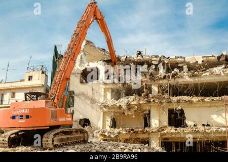 Athens, Greece - February 11, 2020. Building demolition with hydraulic excavator Stock Photo