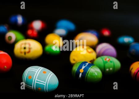 multicolored wooden eggs on black background Stock Photo