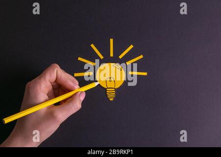 A yellow pencil in hand next to a creative painted light bulb. The concept of innovation and creative ideas Stock Photo