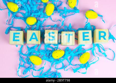 Word Easter on wooden cubes and surrounded with multiple egg decorations as a festive Easter background composition Stock Photo