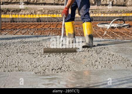 bricklayer at work on a construction site during the laying of concrete to build the foundations of a house Stock Photo