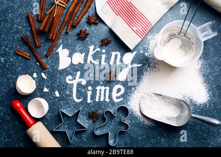 Baking time. Flour sprinkled on the blue table with text baking time. Baking ingredients. Stock Photo