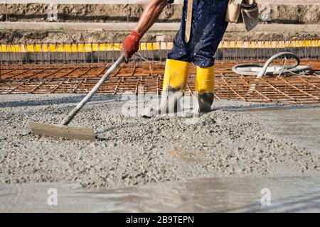 bricklayer at work on a construction site during the laying of concrete to build the foundations of a house Stock Photo