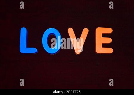 love word written with different colored letter blocks arranged on a dark background Stock Photo