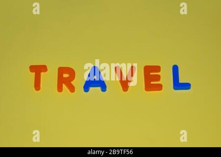 Travel word written with different colored letter blocks arranged on a yellow background Stock Photo