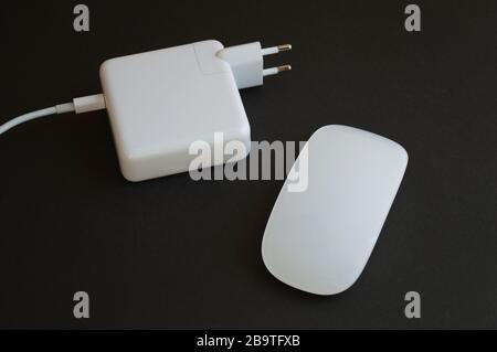 Minimalistic combination of white mouse and charger for laptop on the dark background Stock Photo