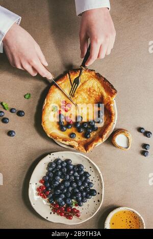 Young Man Hands Start Cutting Dutch Baby Pancake In Ceramic Plate Served With Blackberry And Red Currant Berries Bowl Of Honey Jug Of Cream Vintage Stock Photo Alamy