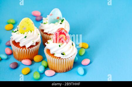 Easter vanilla cupcakes on blue background, copy space Stock Photo