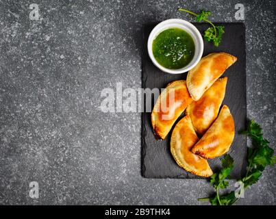 Empanadas with chimichuri sauce. Traditional Latin American cuisine. Top view, copy space