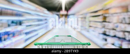 Supermarket aisle with empty green shopping cart Stock Photo