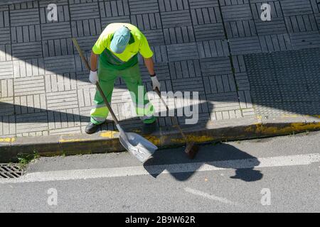 Street sweeper with broom and shovel working on city. Public cleaning concept Stock Photo