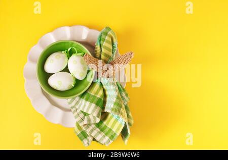 Happy Easter table setting with Easter decoration eggs on yellow background, top view, flat lay, copy space Stock Photo