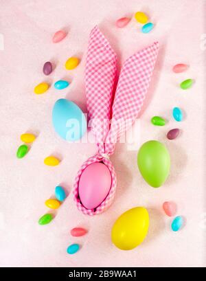 Napkin Easter Bunny, decoration eggs and Easter candy on pink background. Stock Photo