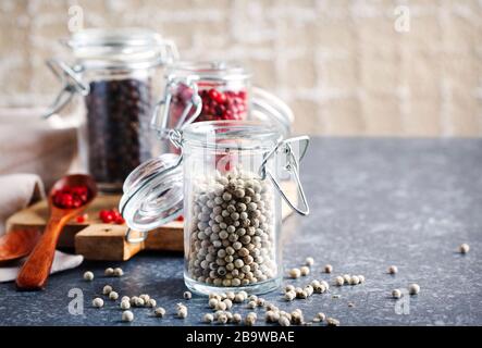 White, pink and black peppers in a glass jars, copy space Stock Photo