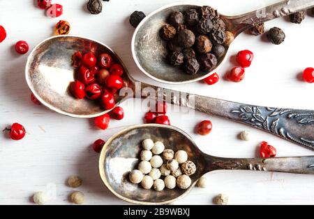 Pink, White and black peppers in spoons, top view Stock Photo