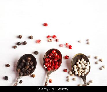 Pink, White and black peppers in spoons, top view, copy space Stock Photo