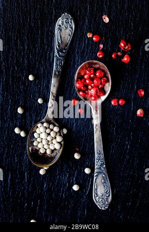White and pink peppers in spoons, top view Stock Photo