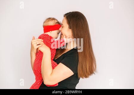 Mom holds a newborn daughter in her arms. Red clothes. The concept of family, motherhood and child care. Stock Photo