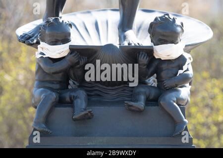 25 March 2020, Saxony, Dresden: Cloths are tied around the mouth of two bronze putti on the Marie Gey fountain. To contain the coronavirus, Saxony now bans all accumulations of three or more in public. Photo: Sebastian Kahnert/dpa-Zentralbild/dpa Stock Photo