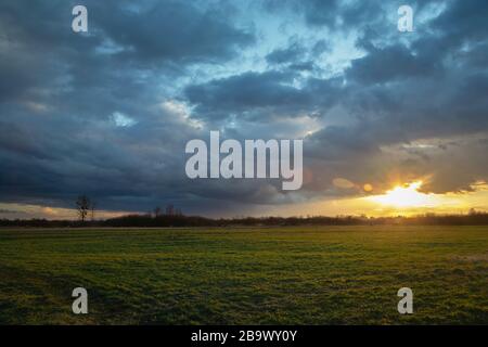 Rainy sky and sunset over the green meadow Stock Photo