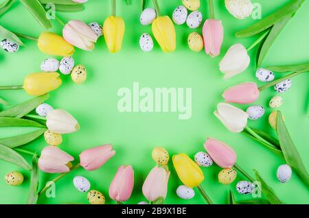 bouquet o tulips and Easter decorited eggs on green background. Spring or  Easter holiday concept, Copy space, flat lay, Template mockup greeting card Stock Photo