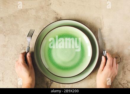 Female hands with cutlery and green empty plate, top view Stock Photo