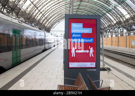 25 March 2020, Saxony, Dresden: On a digital display board on a platform in the main station, it says 'When on the move - then at a distance'. To contain the coronavirus, Saxony now bans all accumulations of three or more people in public. Photo: Sebastian Kahnert/dpa-Zentralbild/dpa Stock Photo