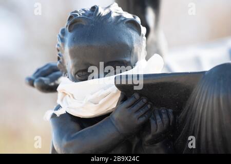 25 March 2020, Saxony, Dresden: A cloth cloth is tied around the mouth of a bronze cherub on the Marie-Gey fountain. To contain the coronavirus, Saxony now bans all accumulations of three or more people in public. Photo: Sebastian Kahnert/dpa-Zentralbild/dpa Stock Photo