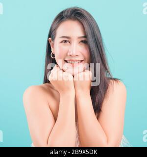 Asian happy portrait beautiful young woman standing smiling surprised excited her keeps hands pressed together under the chin and looking to camera on Stock Photo