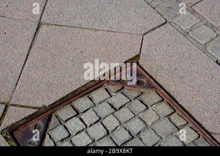 iron manhole with paving stones and granite plates floor in the city, walkside with rusty manhole near paving stones Stock Photo
