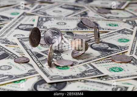 Silver coins falling on United States of America one dollar bills. Concept of finance, economy and business Stock Photo