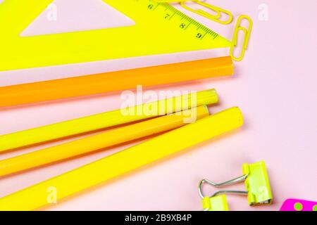 Multi-colored red yellow pinc pencils rulers, pens, pencils and scissors and stationery stand on a pink background Stock Photo
