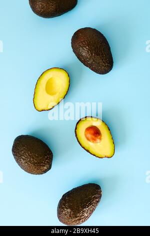 Avocado halves and whole on a blue speckle, top viev. Stock Photo