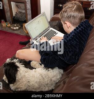 Boy works on his school work at home as schools are shut. Stock Photo