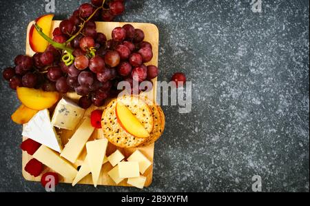 Cheese, creckers and fruits on wooden background Stock Photo