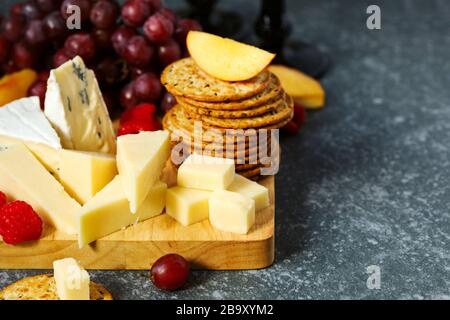 Cheese, creckers and fruits on wooden background Stock Photo