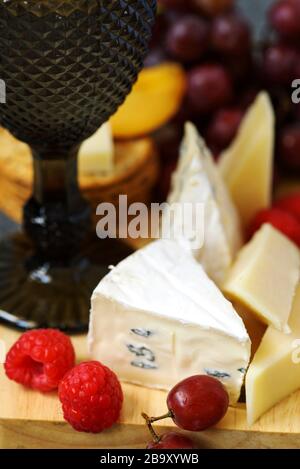 Cheese, creckers and fruits on wooden background Stock Photo