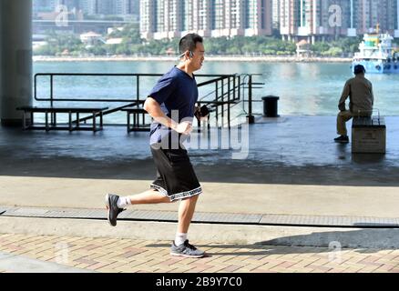 Hong Kong, China. 23rd Mar, 2020. A citizen runs by the sea in Hong Kong, south China, March 23, 2020. People in Hong Kong take part in various forms of exercises amid the COVID-19 epidemic. Credit: Lo Ping Fai/Xinhua/Alamy Live News Stock Photo
