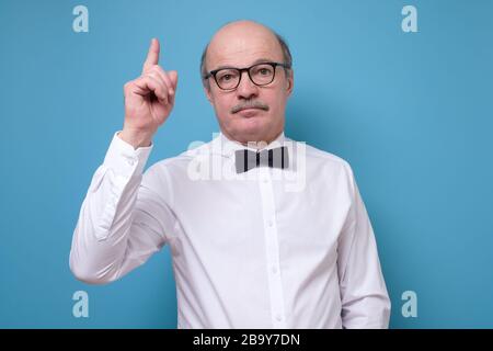 Strict senior man showing index fingers up, giving advice Stock Photo