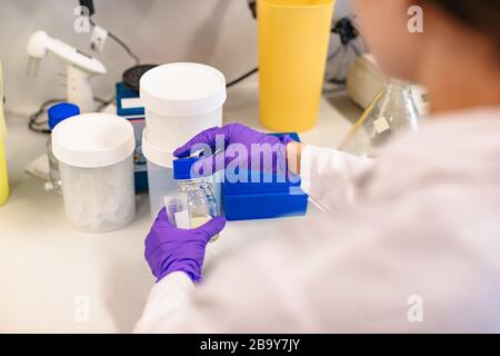 Scientist holding flask in front experiment boxes Stock Photo