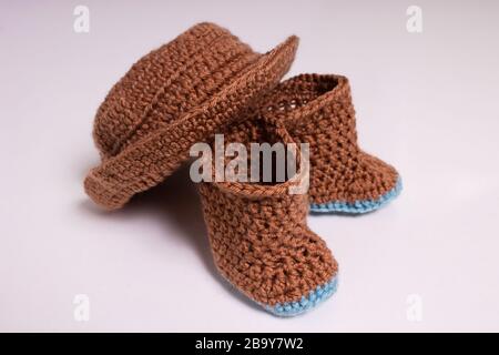 Knitted hat and boots. Knitted shoes and clothes. Booties for babies. Stock Photo