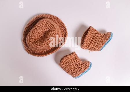 Knitted hat and boots. Knitted shoes and clothes. Booties for babies. Stock Photo