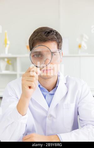 The male doctor looking through the magnifying glass in the lab Stock Photo