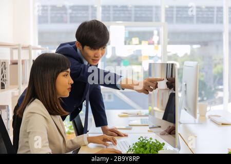 Two male and female staff Asians helped to plan a table full of documents and tablets, notebooks. Stock Photo