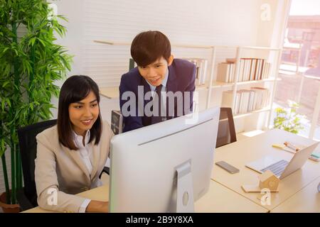 Two male and female staff Asians helped to plan a table full of documents and tablets, notebooks. Stock Photo