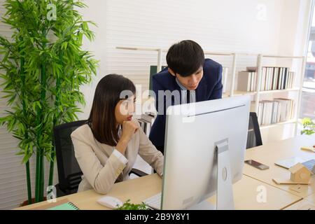 Two male and female staff Asians helped to plan a table full of documents and tablets, notebooks. Stock Photo